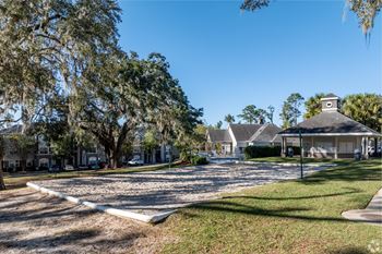 A sunny day at a park with a gazebo and trees.